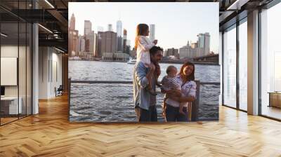 Young family with daughters standing on quayside, side view Wall mural