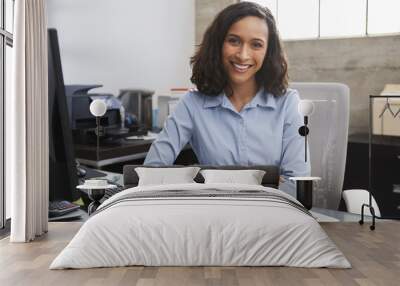 Young female professional at desk smiling to camera Wall mural