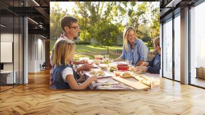 Young white family enjoying a picnic at a table in a park Wall mural