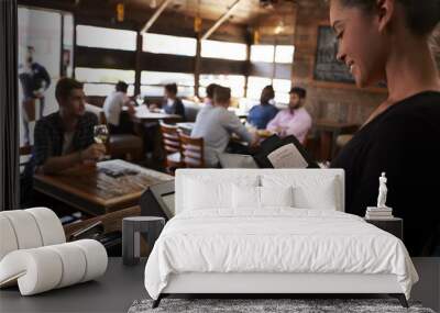 Young woman preparing bill at restaurant using touch screen Wall mural