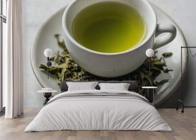 A cup of green tea on a saucer with dry tea leaves Wall mural