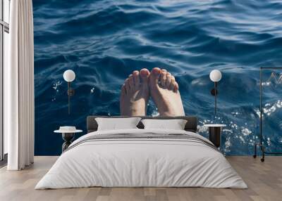 Woman feet in blue sea water Wall mural