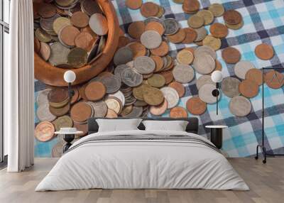 Pile of coins Baht currency is poured out the Pottery cup on the loincloth silk background. Wall mural