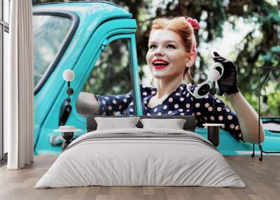 Beautiful stylish woman in vintage bright dotted clothes and glasses is driving mint old car after shopping. Fashion pin-up girl is travelling by auto. Retro style concept. Vacation trip mood. Wall mural