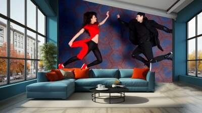 Couple of hip hop / R&B / break dancers jumping to each other wearing in stylish modern red and black cloth on industrial background with rusty hexagonal cells Wall mural