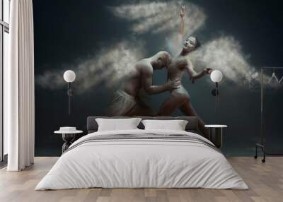 Dancing in flour concept. Girl woman female wearing white dress and guy man male making dance element in flour / white dust in form of wings as angels on isolated black / grey background Wall mural