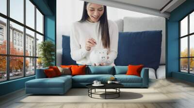 Asian woman putting coin in piggy bank. Save money and investment concept Wall mural