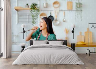 Asian young woman dancing in kitchen room. Female happy and relaxing at free time on weekend Wall mural