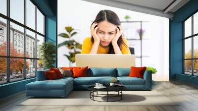 Asian young woman seriously working on computer laptop in house. She thinking find solution problem of work Wall mural