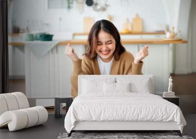 Funny euphoric young asian woman celebrating winning or getting ecommerce shopping offer on computer laptop. Excited happy girl winner looking at notebook celebrating success Wall mural