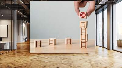 Hand arranging wood block stacking on top with wooden table. Concept of trying to achieve objectives Wall mural