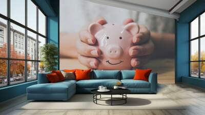 Panoramic image, Man hand holding piggy bank on wood table. Save money and financial investment Wall mural