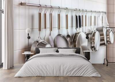 A collection of shiny stainless steel cookware hanging on a modern kitchen rack, emphasizing organization and style. Wall mural