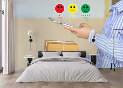 young woman hand holding smartphone and putting check mark with smiley face marker and green marker on five stars of delivery package, Satisfaction evaluation and Postal service concept Wall mural