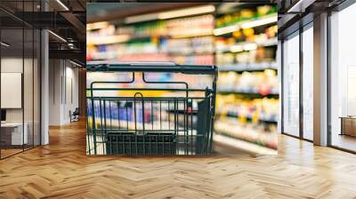 Shopping cart on the background of shop shelves in a supermarket Wall mural