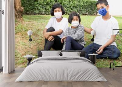 Three asian children two girl and one boy lay down on grass floor in the park. Wall mural