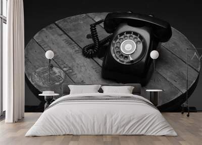 Old black phone with dust and scratches, isolated on wooden retro floor Wall mural