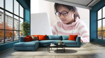 A cute girl uses a laptop. A teenage girl in casual clothes looks at a laptop screen while at home. Online Education Wall mural