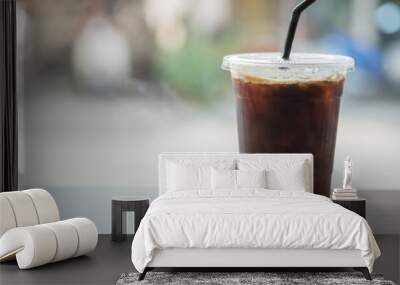 Close up of take away plastic cup of iced black coffee (Americano) on wooden table. Wall mural