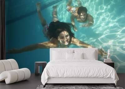 A happy young couple swimming underwater in pool Wall mural