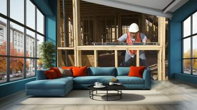 An African American man measuring level of a wooden beam with spirit level Wall mural