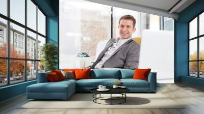 Attractive businessman sitting and relaxing in his office Wall mural