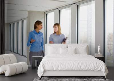 Businesswomen talking while walking in office corridor Wall mural