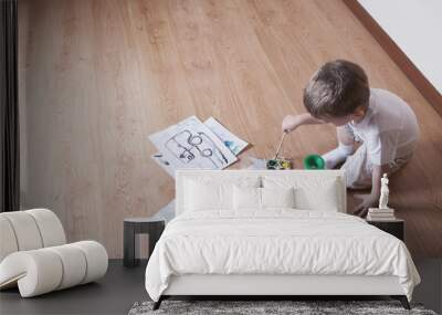 Elevated view of young boy painting with watercolors and paintbrush on laminated floor Wall mural