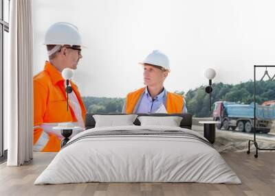 Engineers discussing at construction site against clear sky Wall mural