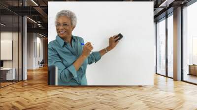 Female teacher erasing text on whiteboard in classroom Wall mural