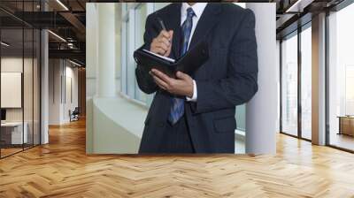 Happy African American businessman holding dairy while leaning by window Wall mural