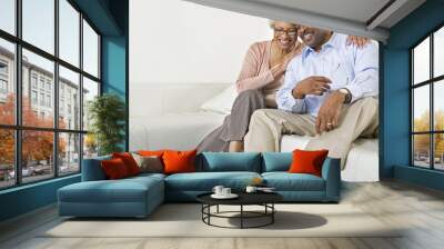 Happy African American senior couple sitting on sofa at home Wall mural