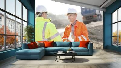 happy engineer discussing with colleague at construction site on sunny day Wall mural