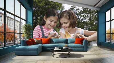 Happy little girls looking into jar outdoors Wall mural