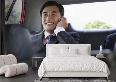 Happy young businessman using cellphone in backseat of car Wall mural