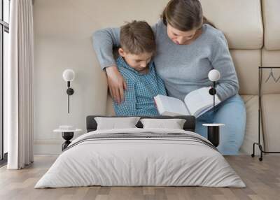 High angle view of mother and son reading book on sofa Wall mural