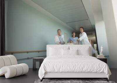 Low angle view of physicians rushing patient on gurney down hospital corridor Wall mural