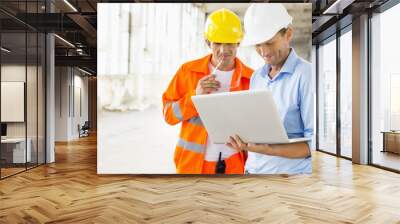 Male architects using laptop at construction site Wall mural