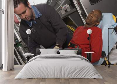 Male EMT professional taking care of a senior man inside ambulance Wall mural