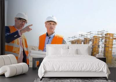 Male engineers discussing at construction site against clear sky Wall mural