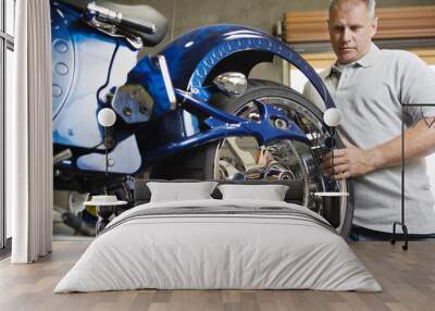 Male mechanic fixing motorcycle in a garage Wall mural