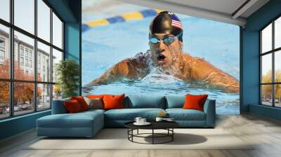 male professional swimmer wearing goggles and cap swimming in a pool competition Wall mural