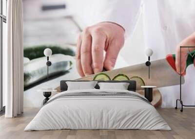 Midsection of mature chef cutting cucumber on board in restaurant kitchen Wall mural