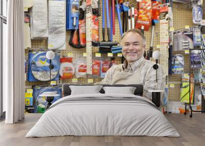 Portrait of a happy mature salesperson with arms crossed in hardware store Wall mural