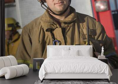 Portrait of a middle aged male firefighter holding axe with man in the background Wall mural