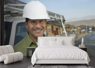 Portrait of a smiling construction worker in hardhat standing next to truck on construction site Wall mural