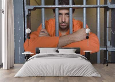 Portrait of an unhappy prisoner holding prison bars Wall mural