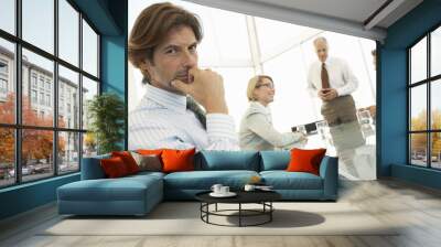 Portrait of handsome businessman with colleagues discussing at conference table Wall mural