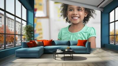 Portrait of smiling little girl assembling  puzzles in classroom Wall mural