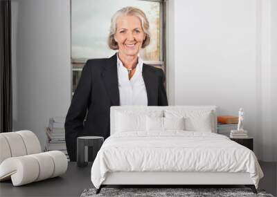 Portrait of smiling senior businesswoman with stack of books on desk in office Wall mural